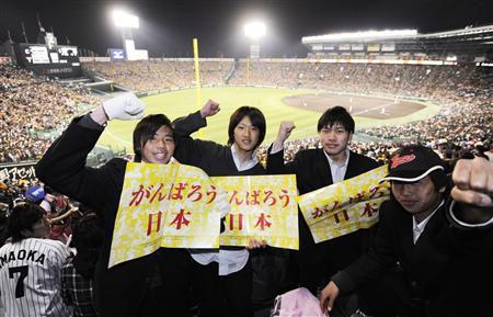プロ野球が開幕した甲子園球場で被災者を応援するメッセージを掲げる、阪神大震災の年に生まれた地元の高校生=12日夜、兵庫県西宮市