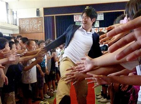 神戸市の母校の小学校で後輩たちから歓迎の握手攻めにあう香川真司選手(2011年6月22日、共同))