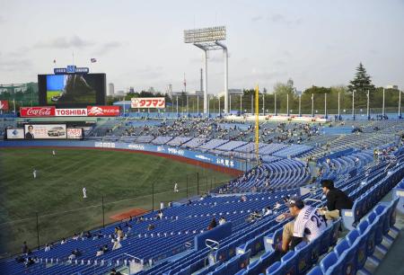 神宮球場の一塁側スタンドから見たスコアボード(左)など外野席の景観。グラウンドでは試合開始前の練習が行われている(共同)