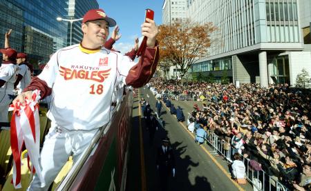 優勝パレードのバスに乗り込み、沿道のファンを携帯電話のカメラで撮影する楽天・田中