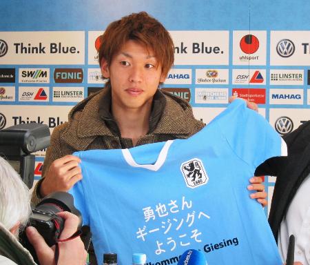 ミュンヘンの入団記者会見でユニホームを手にする日本代表FW大迫勇也=7日、ミュンヘン(共同)