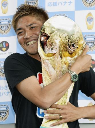 サッカーW杯日本代表に選ばれ、報道陣が用意した手作りのW杯トロフィーを手に笑顔の大久保嘉人=12日午後、羽田空港