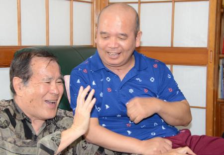 療養生活中の名嘉真堅安さん(右)を訪ね、再会を喜ぶ金城真吉さん(沖縄タイムス提供)