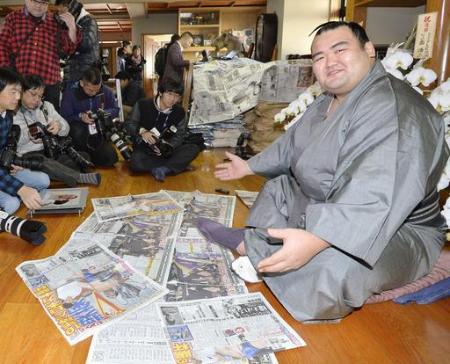 初優勝を報じるスポーツ紙を前に笑顔の大関琴奨菊=千葉県松戸市の佐渡ケ嶽部屋(2016年1月25日、共同)