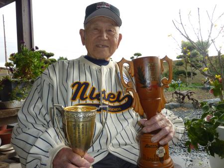 1944年の鶴嶺湖リーグで首位打者の入山正夫さん。首位打者トロフィーを持ち、米野球殿堂での日系野球展の記念ユニホームを着用(共同)