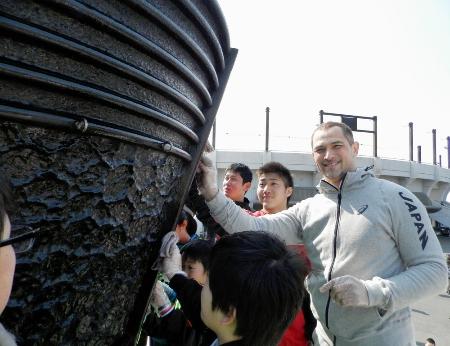 震災からの復興の象徴として貸し出されている1964年東京五輪の聖火台を地元の子どもたちと磨く五輪組織委の室伏広治さん=3月5日、宮城県石巻市