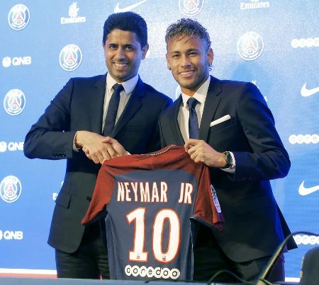 サッカーのフランス1部リーグ、パリ・サンジェルマンに移籍し、入団会見で背番号「10」のユニホームを手にするネイマール選手(右)=4日、パリ(AP=共同)