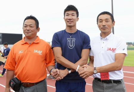 桐生祥秀選手(中央)と握手する、男子100メートル決勝でスターターを務めた福岡渉さん(左)ら=福井県営陸上競技場
