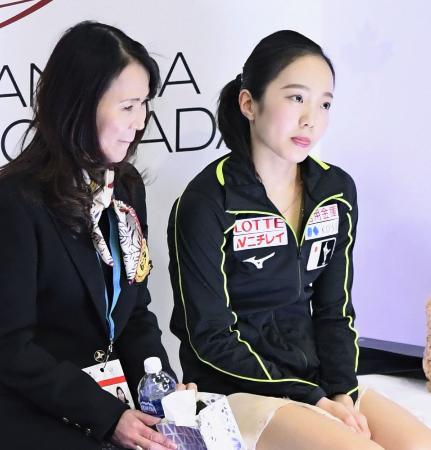 スケートカナダ女子SPの演技を終え、得点を待つ間に舌を出す本田真凜。左は浜田美栄コーチ=レジャイナ(共同)