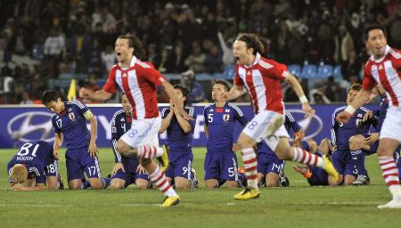 PK戦を制して駆けだすパラグアイ選手と悔しがる本田(奥左端)、駒野(奥右端)ら日本の選手たち=2016年6月29日、プレトリア(共同)