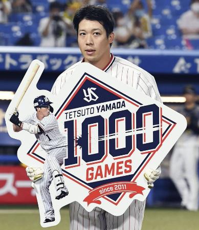 通算千試合出場を達成し、記念のボードを手にするヤクルト・山田哲=神宮