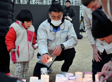 灯籠に火をともすラグビーコベルコ神戸スティーラーズの日和佐篤選手＝１６日、神戸市中央区の東遊園地 