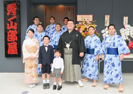 部屋の前で力士や家族らと記念写真に納まる秀ノ山親方(中央)=20日、東京都墨田区