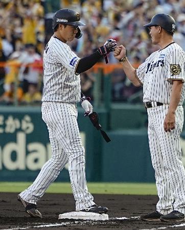1回、先制打を放ちコーチ(右)とタッチを交わす阪神・大山=甲子園