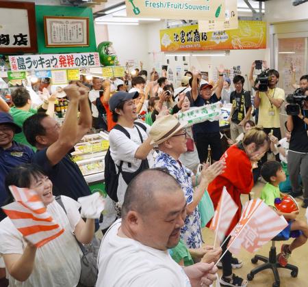 沖縄尚学高の優勝が決まり、那覇市の第一牧志公設市場で喜ぶ人たち=23日午後