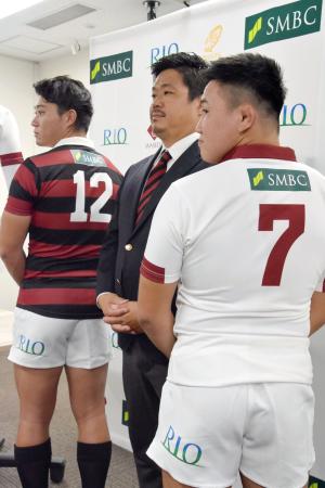 スポンサーのロゴ入りのラグビー部ジャージーを披露する早大の野中健吾主将(左)ら。中央は大田尾竜彦監督=4日、東京都内