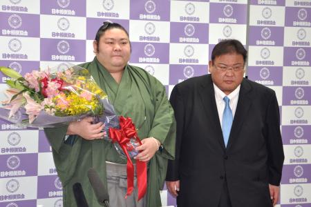 引退記者会見を終え花束を手にする元幕内剣翔。右は追手風親方＝１４日、東京・両国国技館 